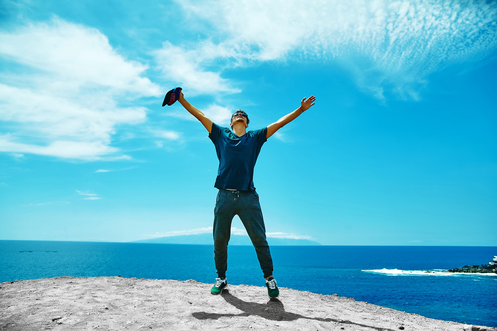 happy-stylish-man-casual-clothes-standing-cliff-mountain
